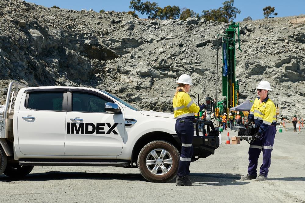 two employees in protective suit and miners drilling behind