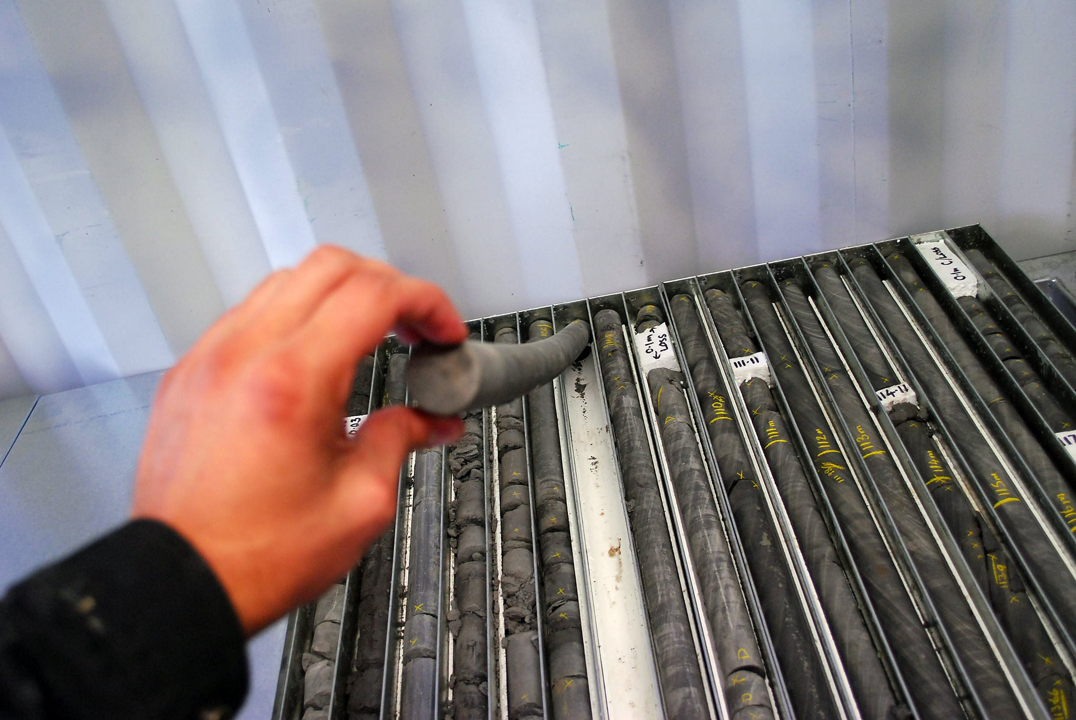 core tray with a hand holding a core sample